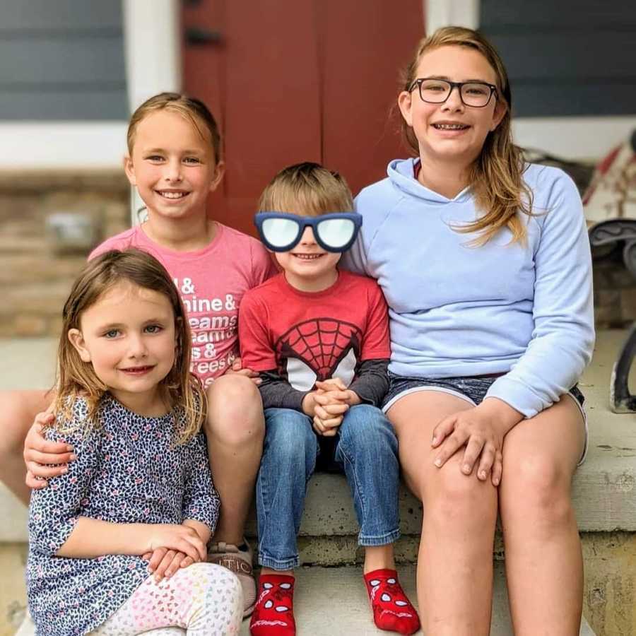 Siblings with foster brother smiling on porch together