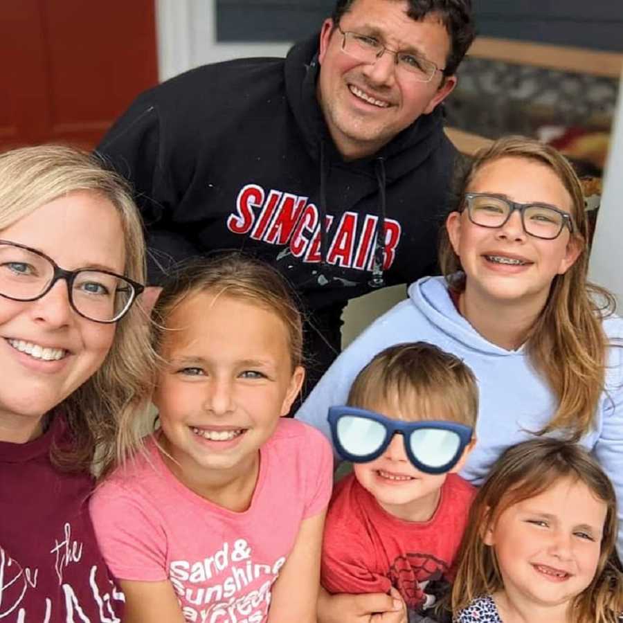 Foster family and foster child posing and smiling on porch