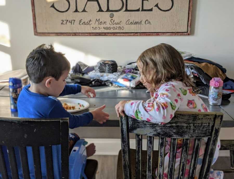 Foster son and sibling eating breakfast together at table talking to each other