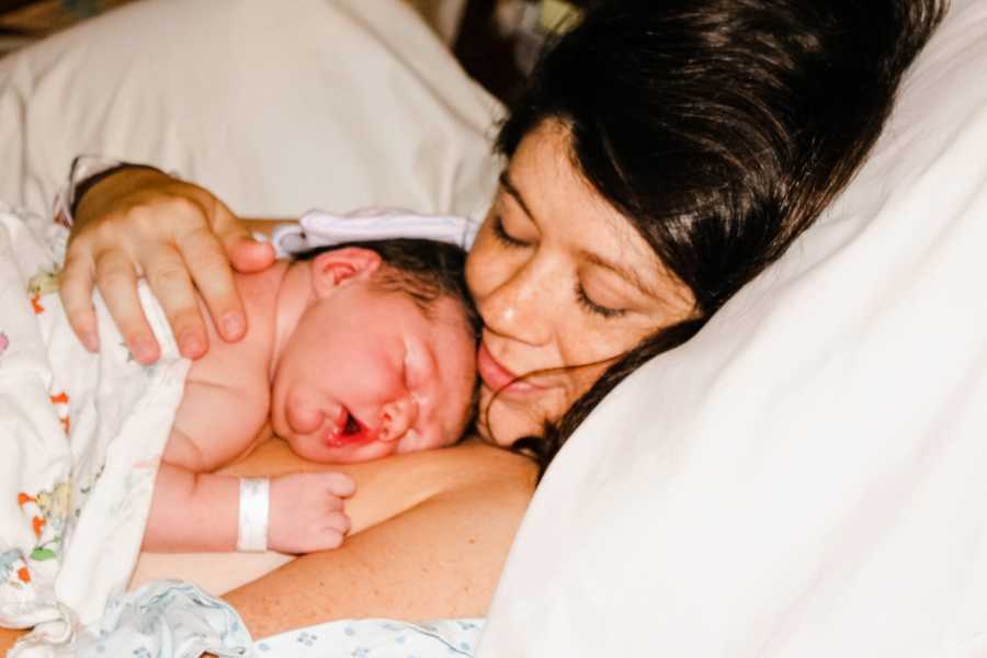 New mom holds newborn baby in hospital bed