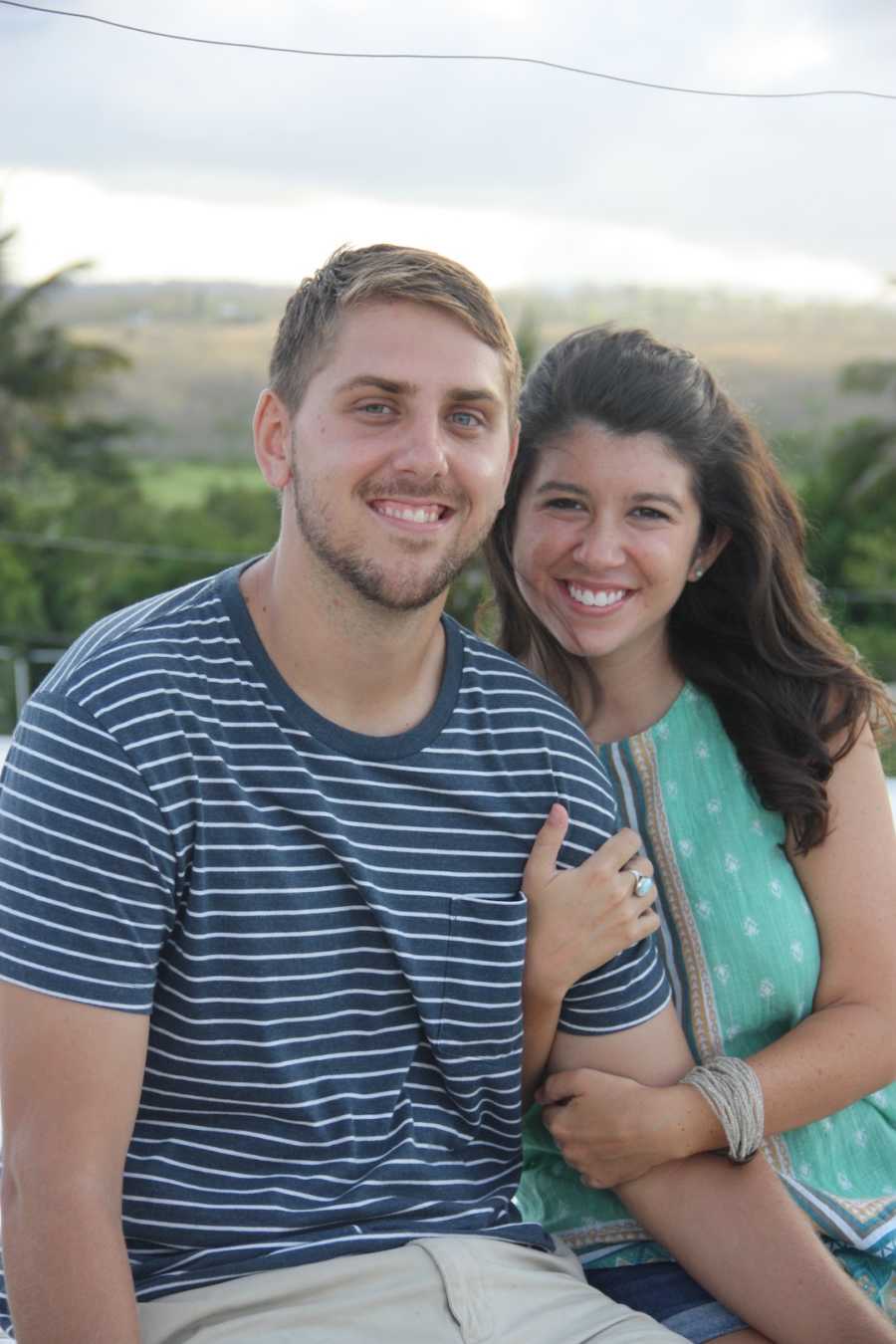 A husband and wife smile in front of a nature background