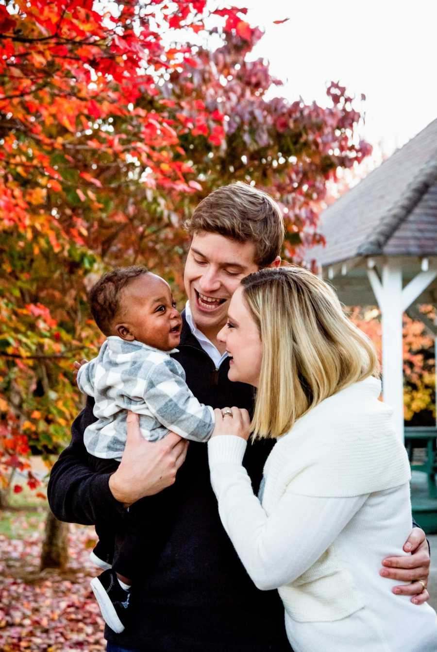 Adoptive parents and their son together in the fall