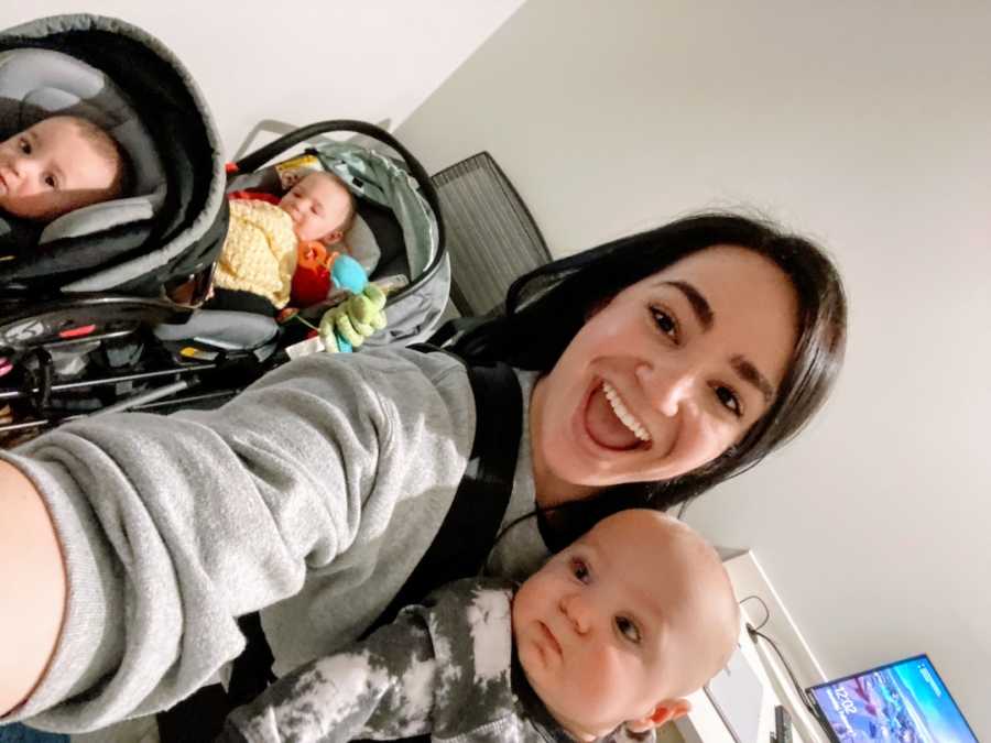 Young mom smiling with three babies in carseats