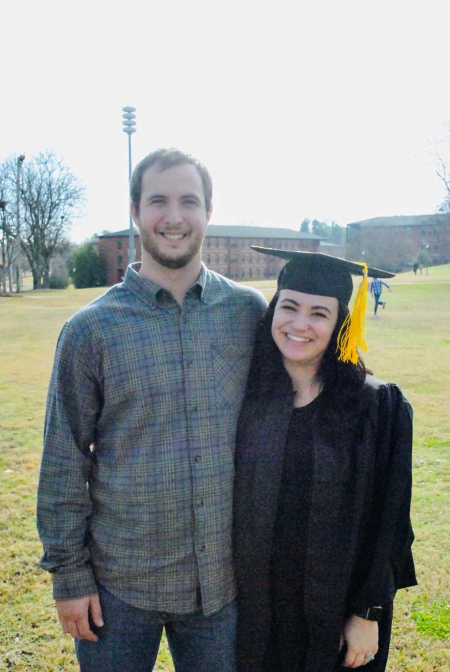 A young pregnant couple smiling after graduation