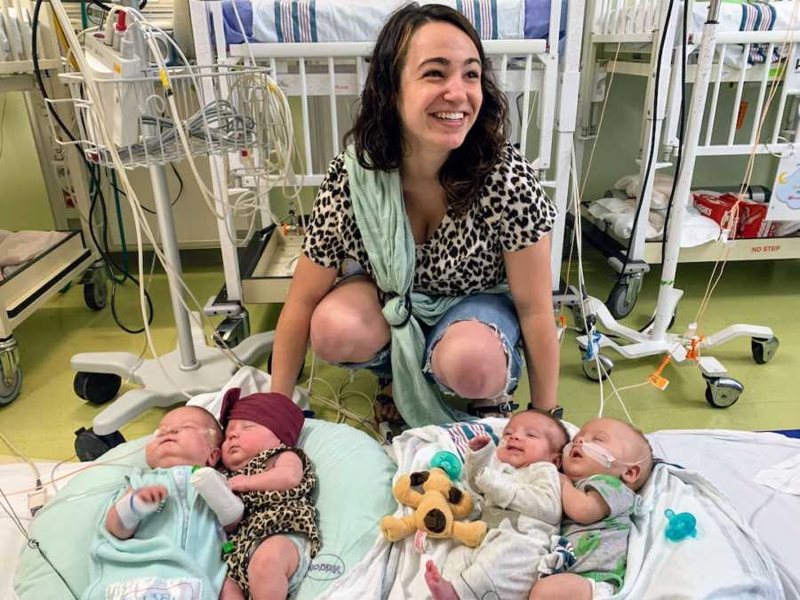 Young mom posing with quadruplets in hospital