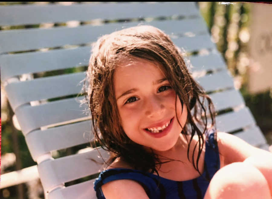 Child sitting by a pool smiling