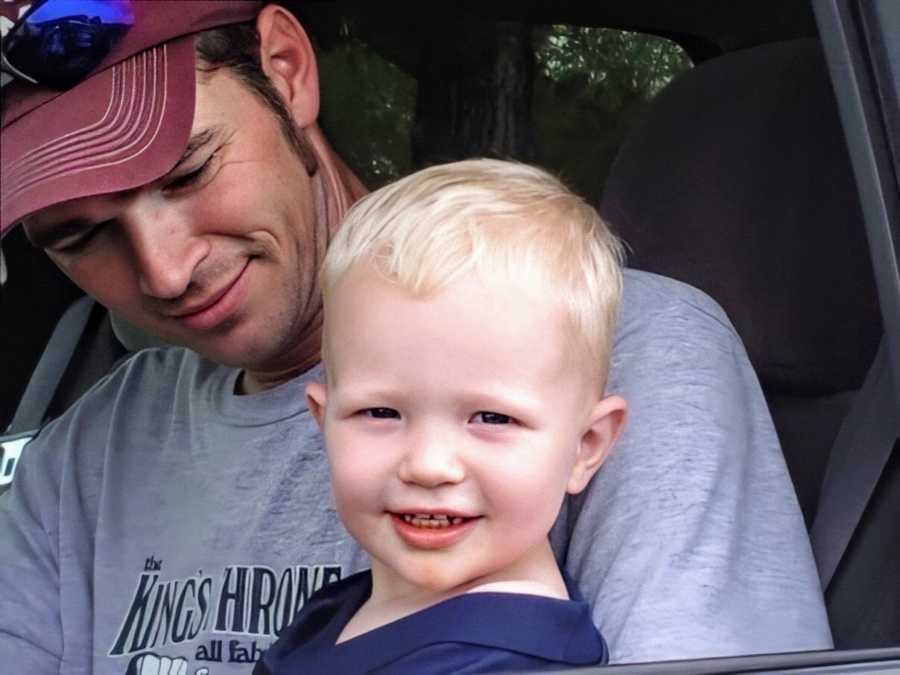 A boy and a man sit together in a car