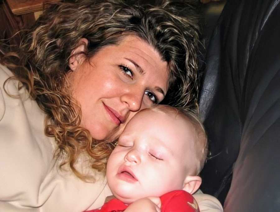 A woman cuddles with a sleeping toddler