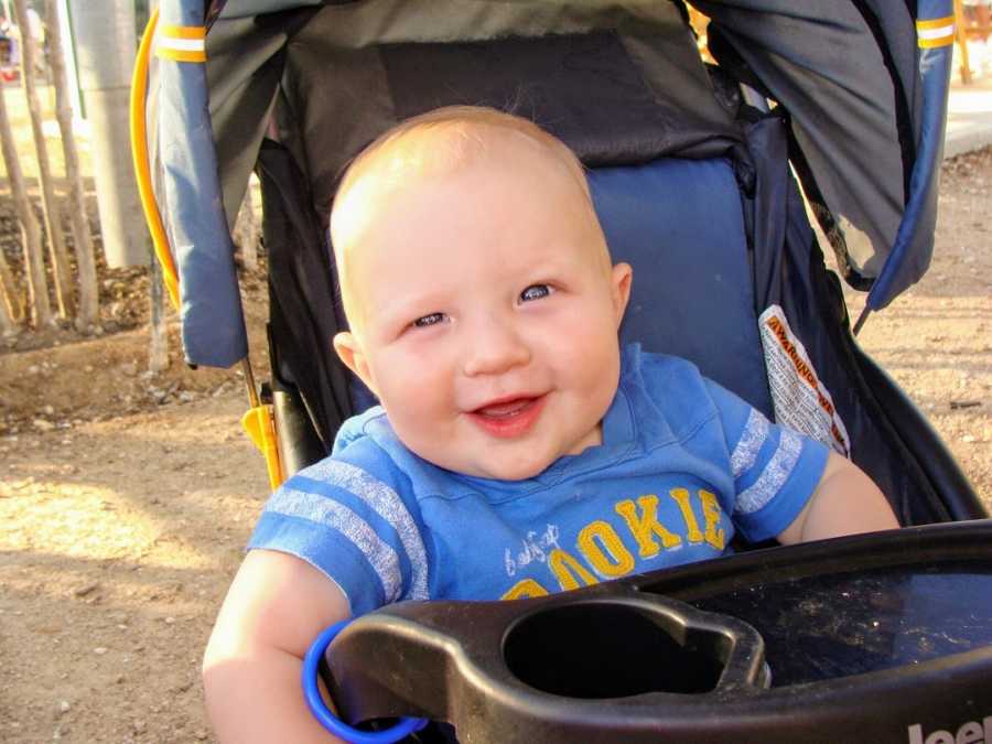 A boy wearing a blue T-shirt sits in a stroller