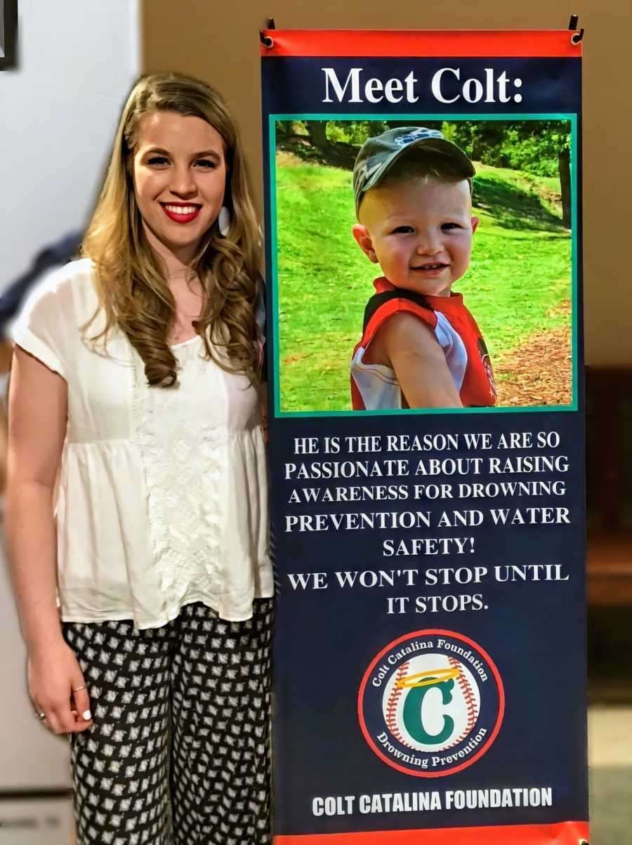 A woman stands next to a sign picturing a drowning victim