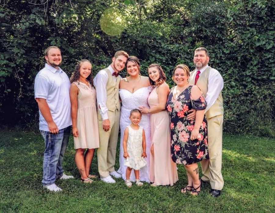 A bride and groom surrounded by their family