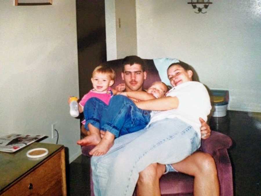 A married couple and their children sit together in an armchair