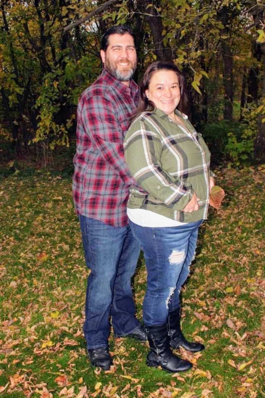 A husband stands with his arms around his wife