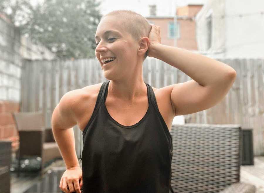 Woman with buzzcut smiling and sitting outside on patio