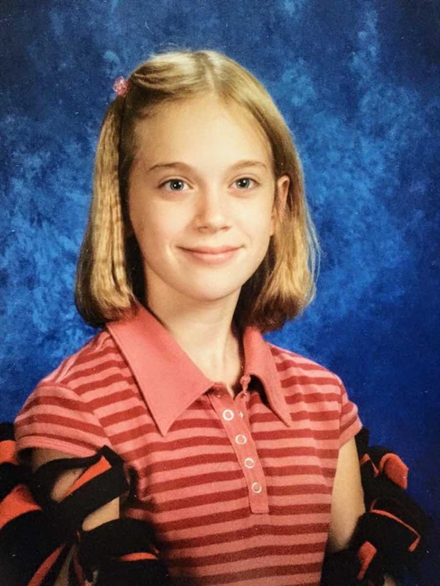 Young girl wearing striped shirt in front of blue background smiling