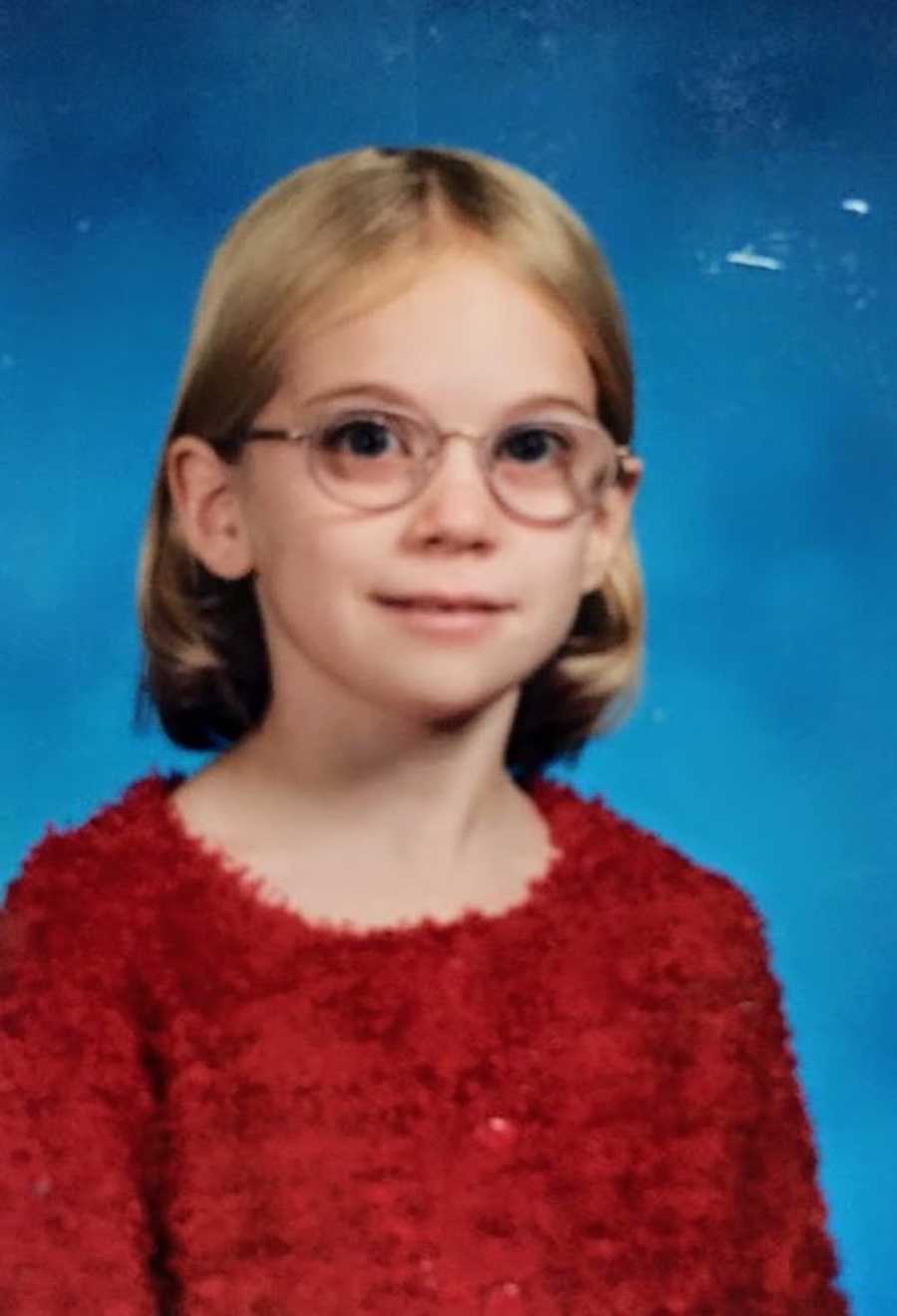 Young girl wearing red sitting in front of blue background