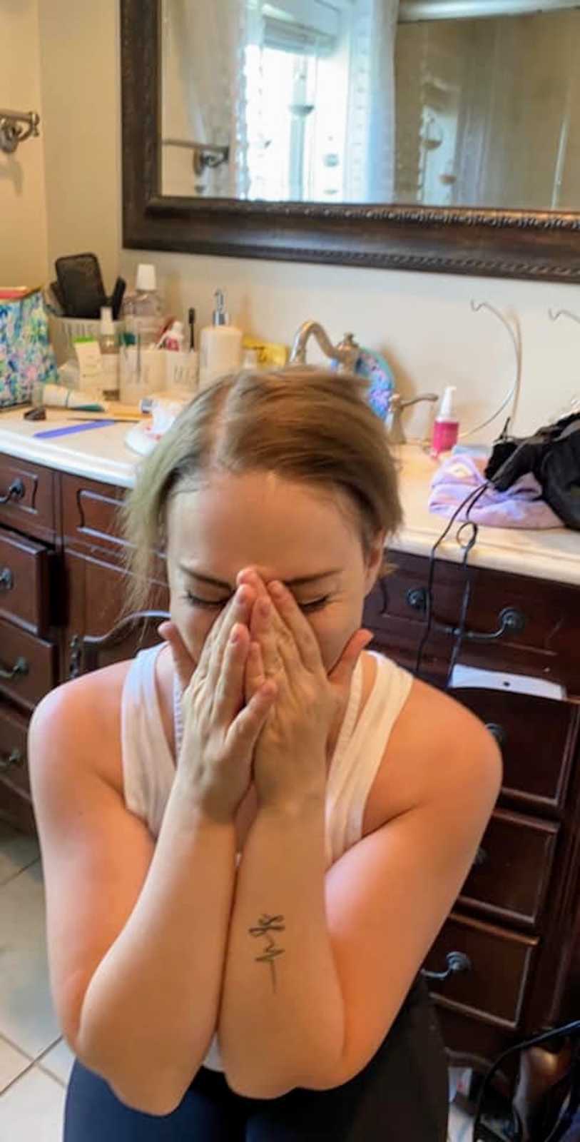 Girl covering face with hands sitting in bathroom