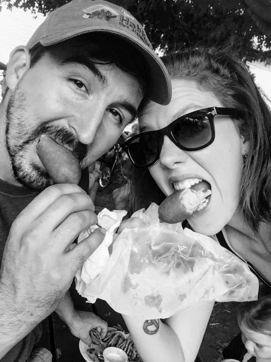 Black and white photo of husband and wife eating corndogs