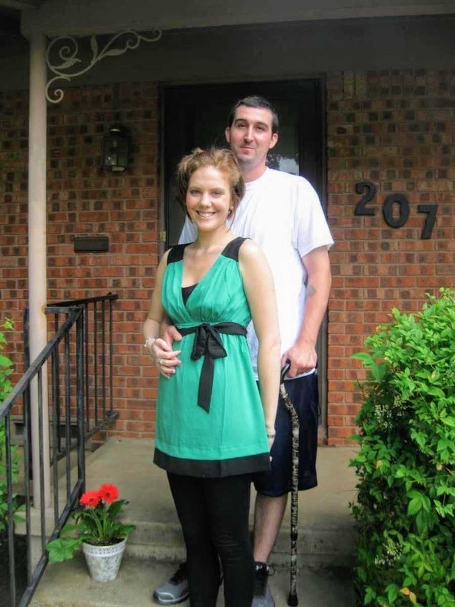 Husband and wife standing on front steps of brick house