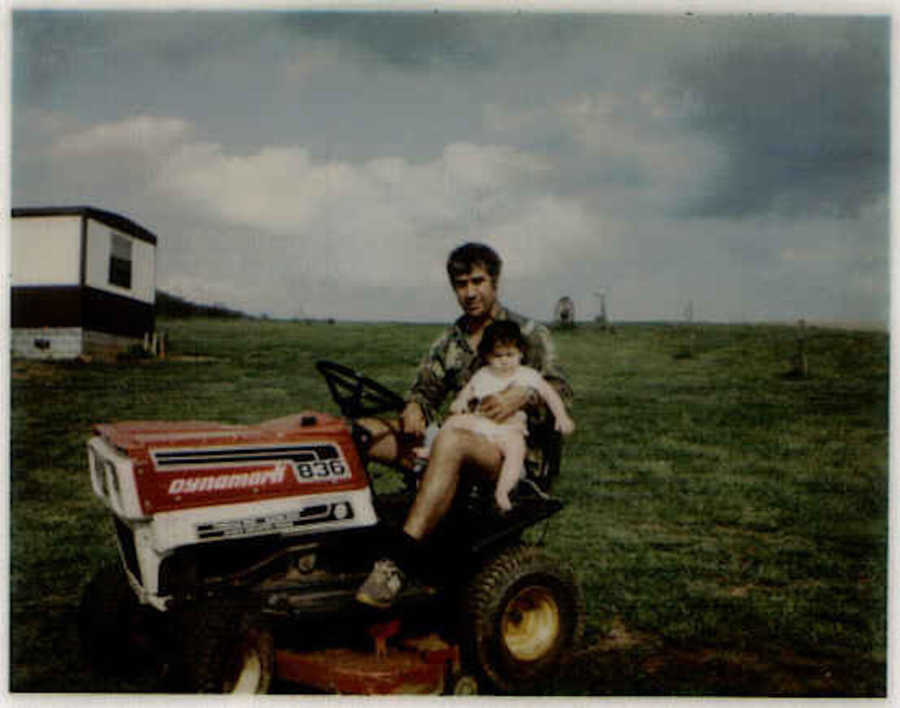 Dad on riding lawnmower holding young daughter