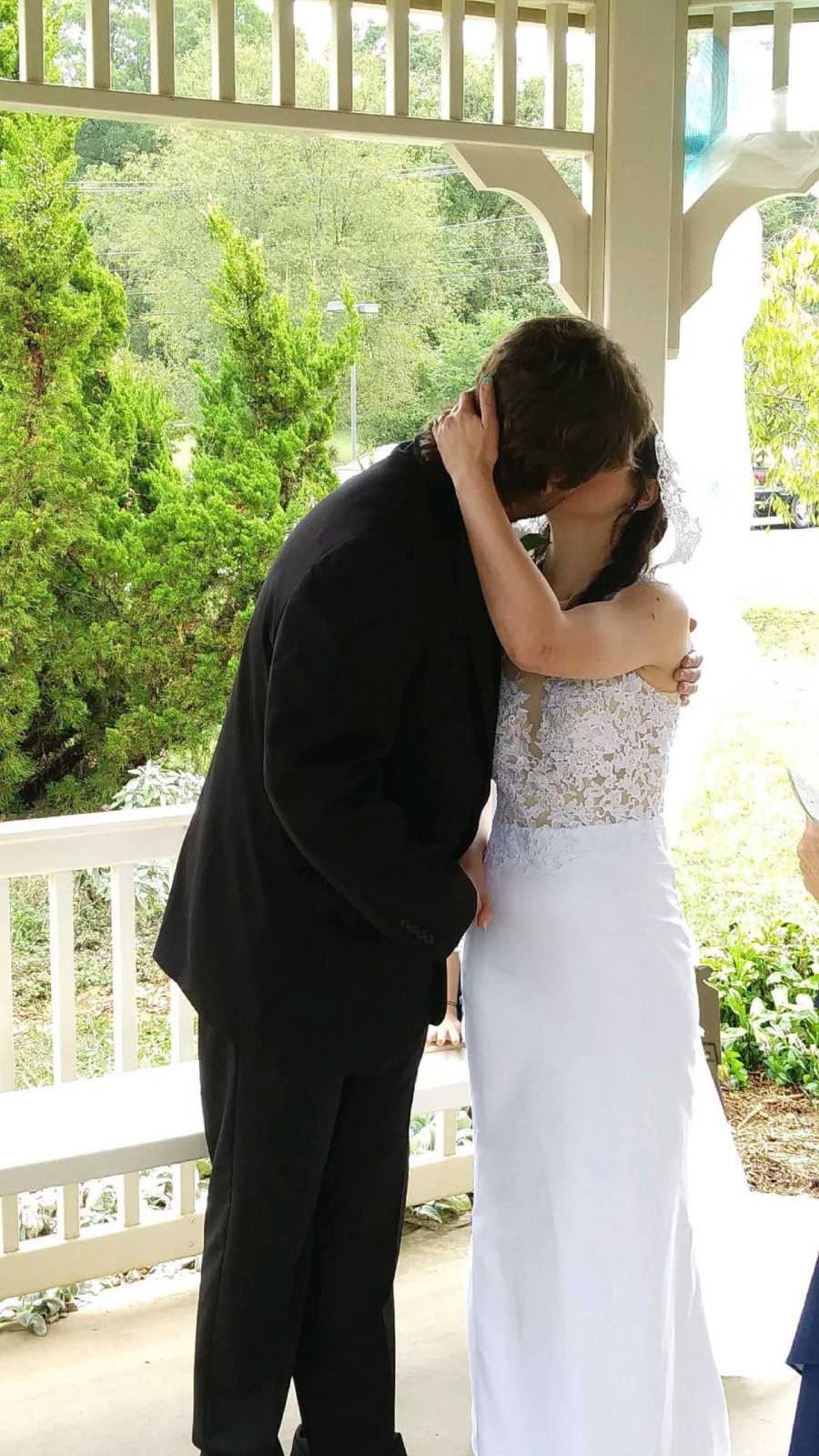 Young bride in wedding dress kissing young groom in suit