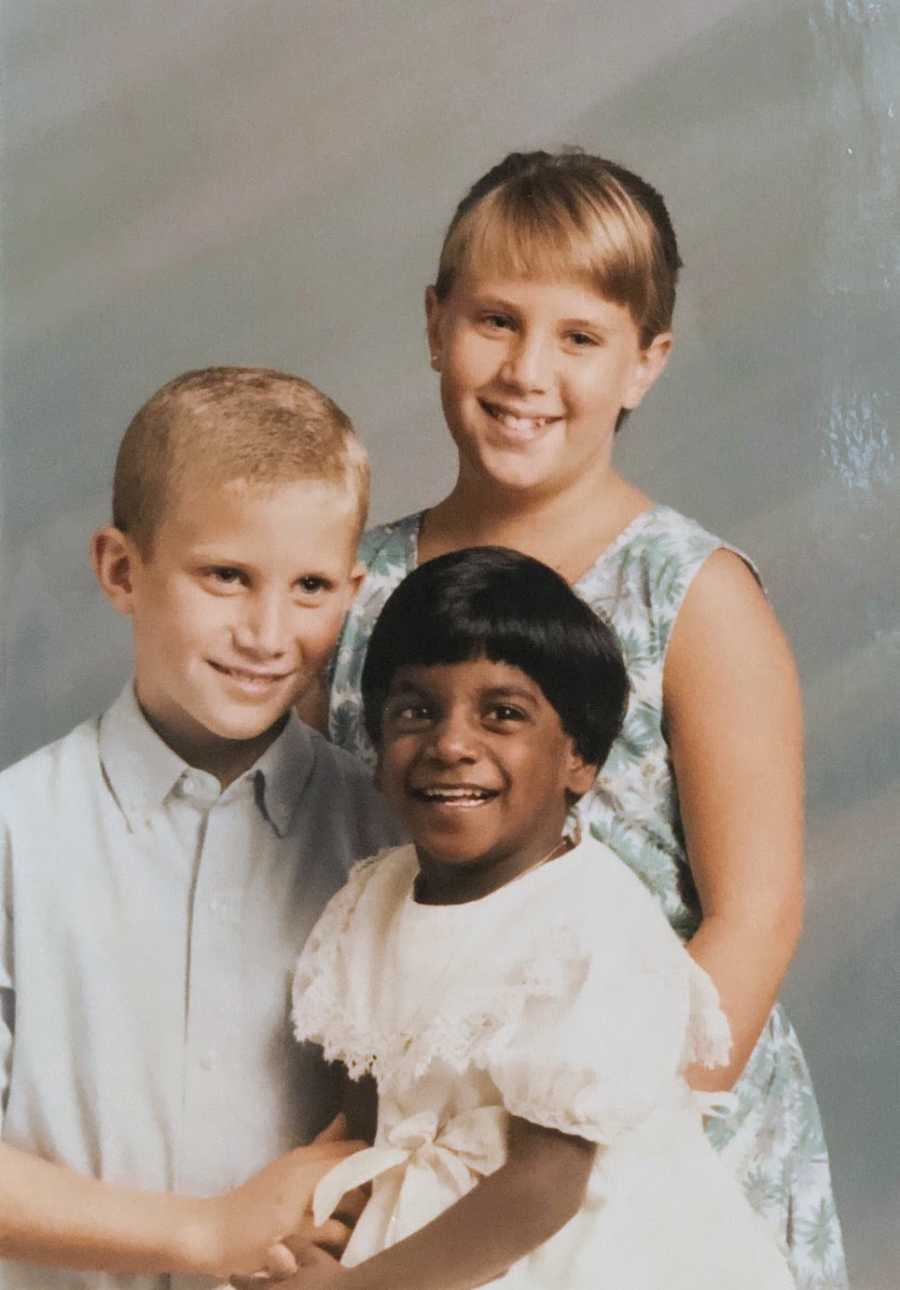 A young Indian adoptee sits with her older siblings