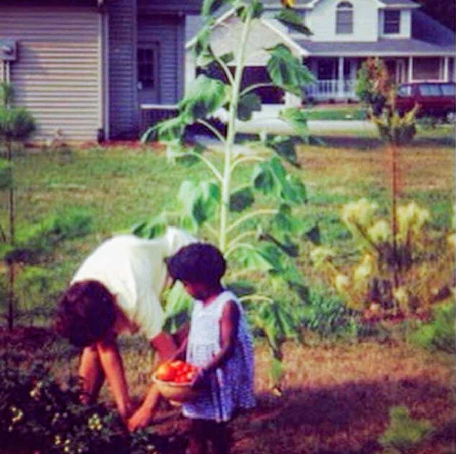 A young adopted girl gardening with her mother
