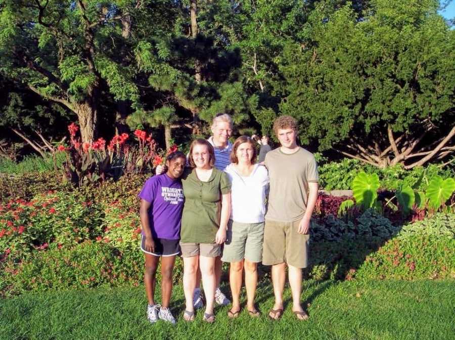 An Indian transracial adoptee and her family stand toegther outdoors