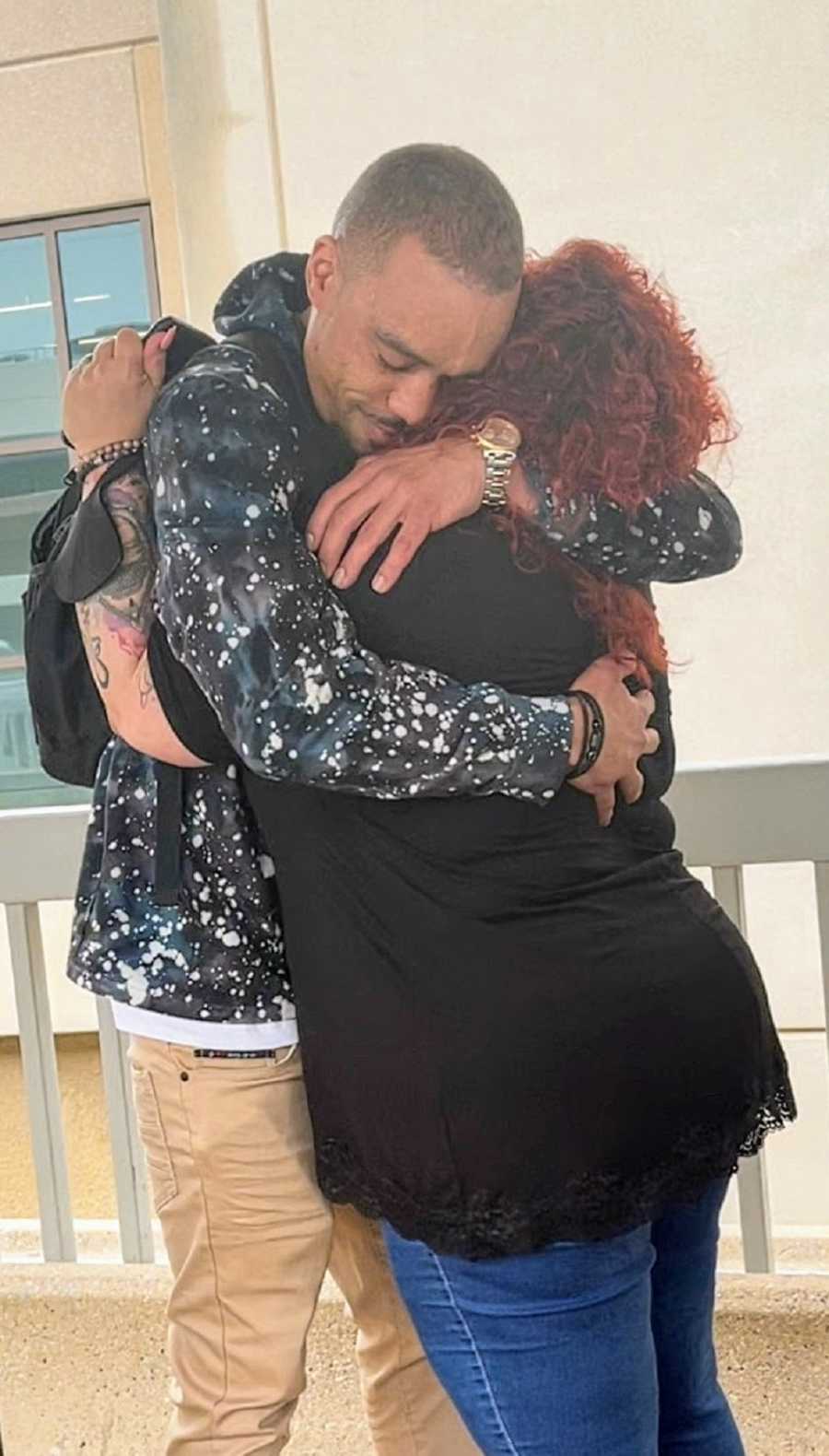 An adult adoptee hugs his birth mother in an airport