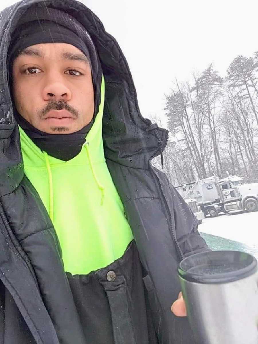 A mixed race man with a moustache dressed in a snow coat