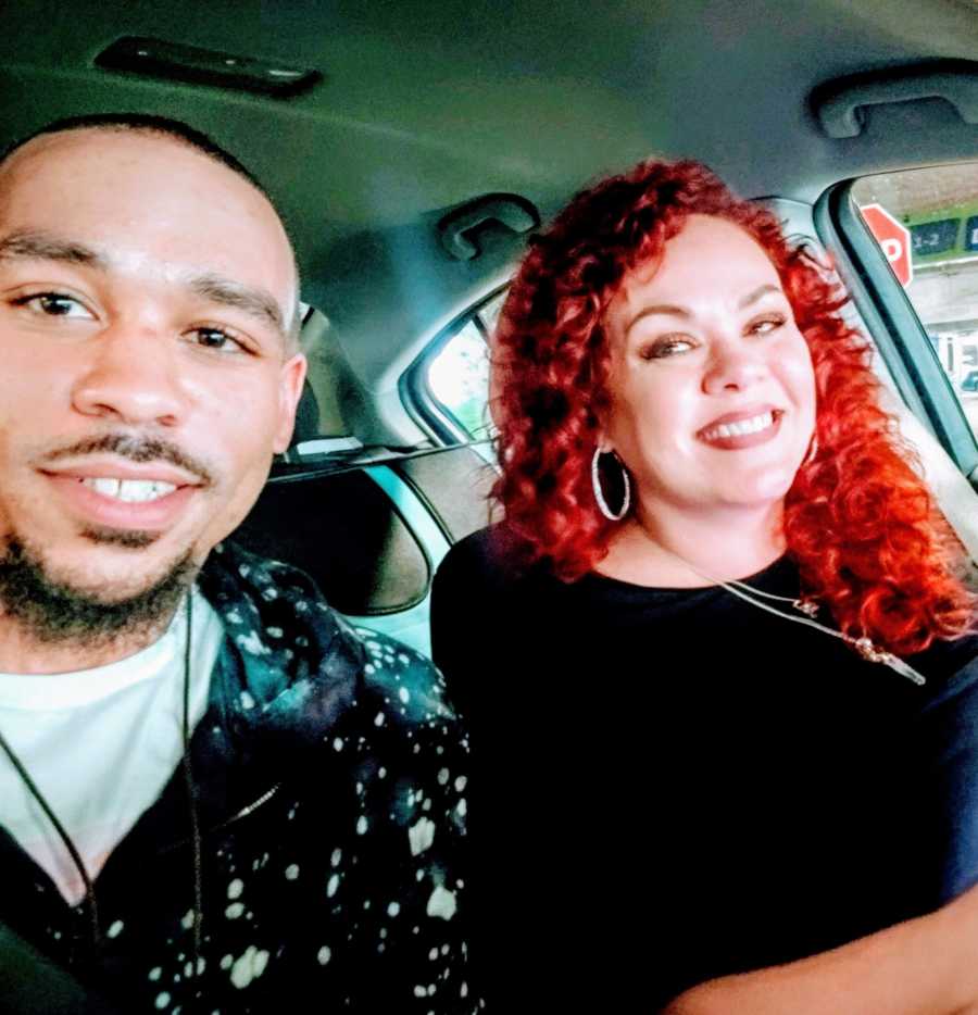 An adult adoptee and his mother sit together in a car