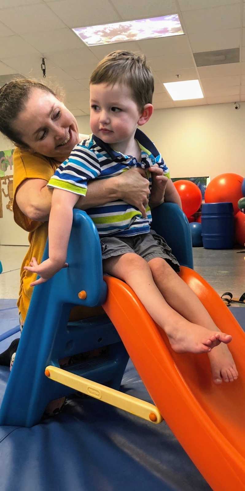 A mom and her son with special needs on a slide