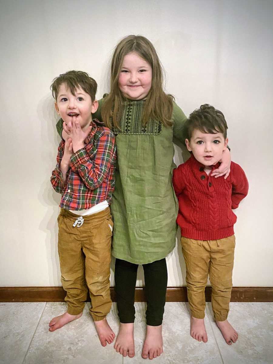 A boy with special needs stands with his brother and sister