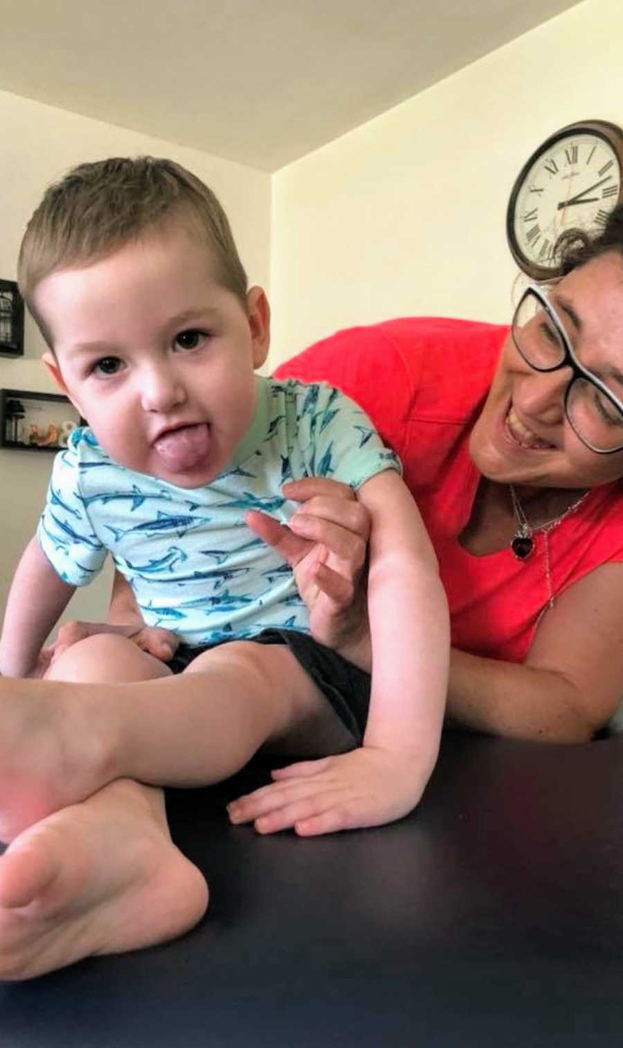 A mother holds her son with special needs as he sticks out his tongue