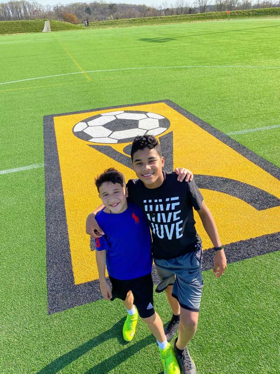 A pair of brothers stand together on a soccer field