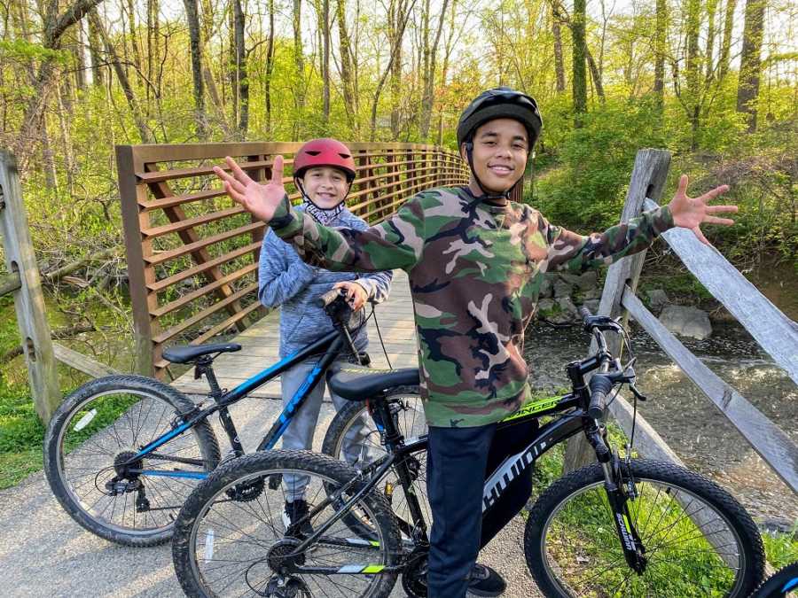 A pair of brothers wait on bikes near a bridge