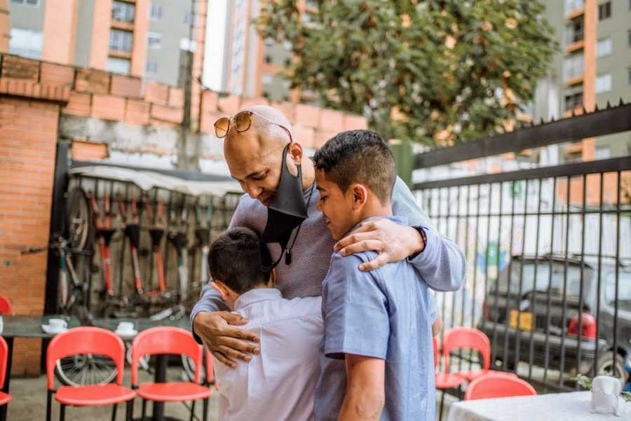 A single adoptive father hugs his sons when he meets them in person