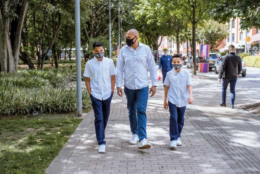 An adoptive father and his sons walk while wearing masks