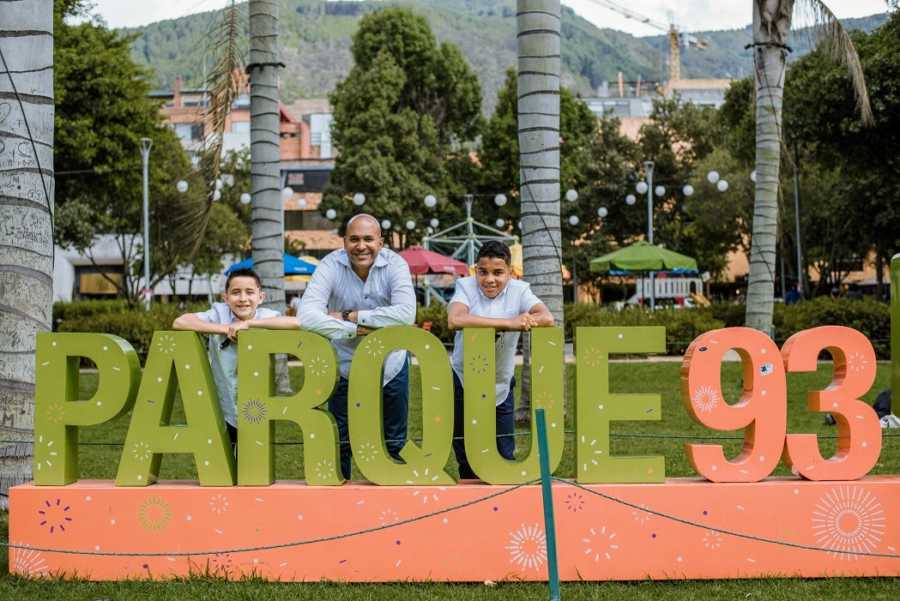 An adoptive father and his sons by a sign reading Parque 93