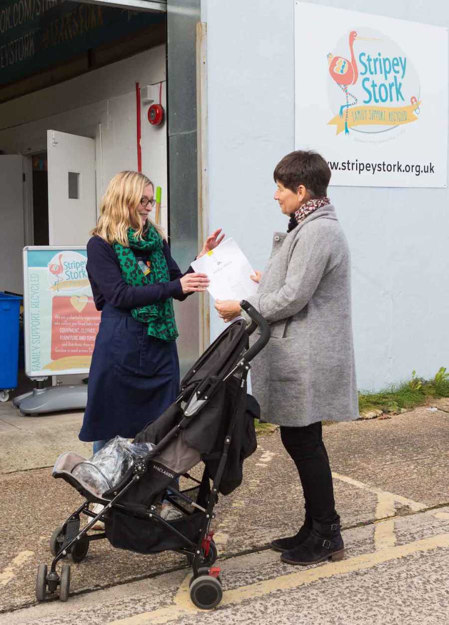 two women with a stroller, sign in back "Stripey Stork"