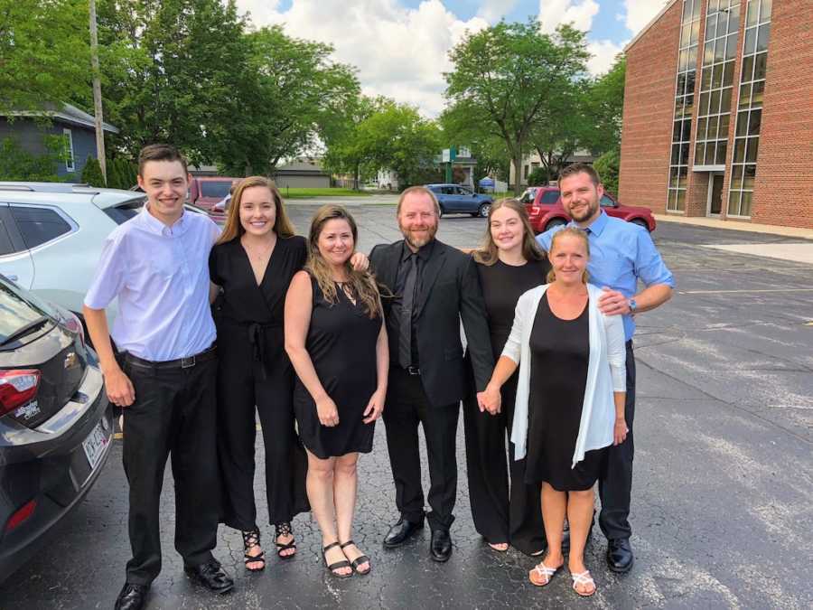 Family standing in parking lot smiling