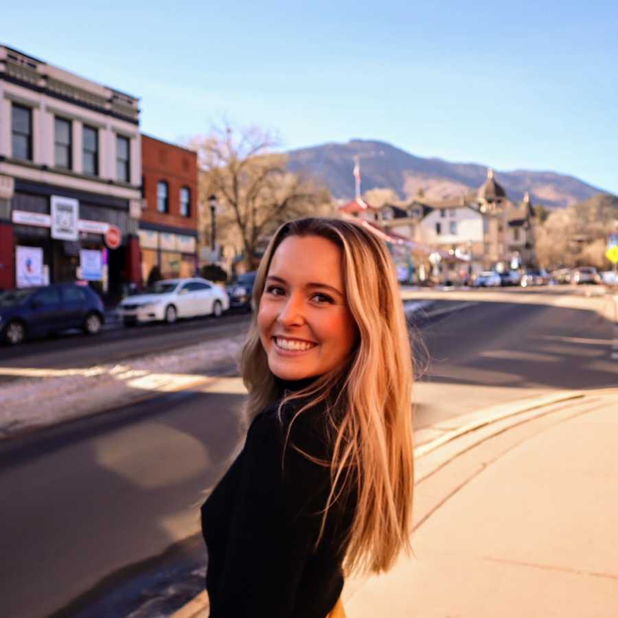 Woman standing in street smiling in the sun