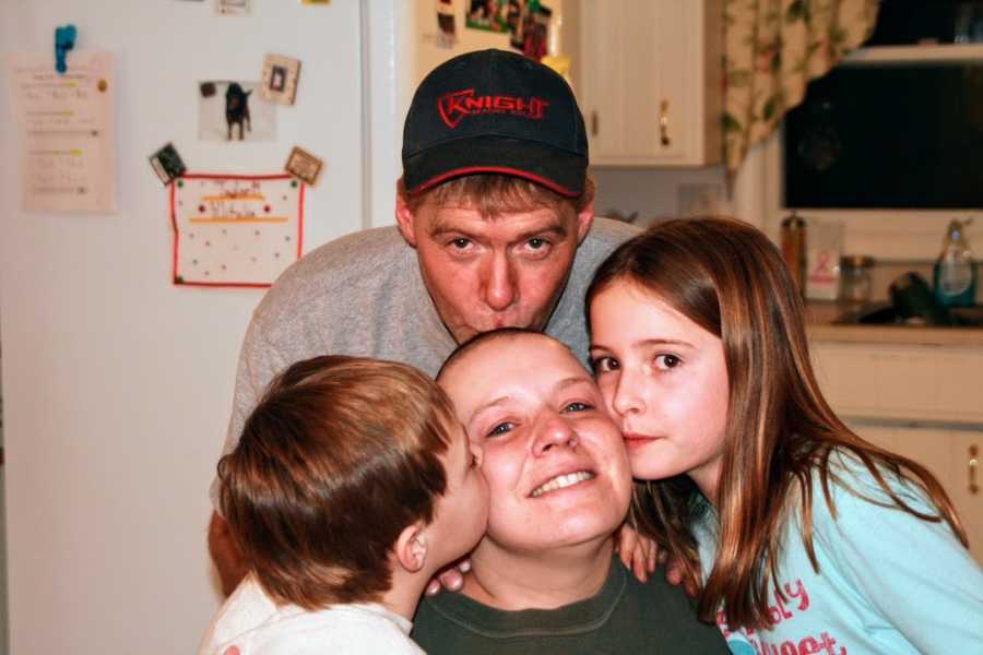 Family of four kissing mother 