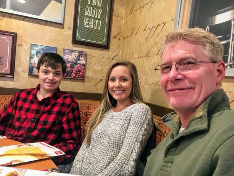 Son, daughter, and father sitting in a booth at restaurant smiling