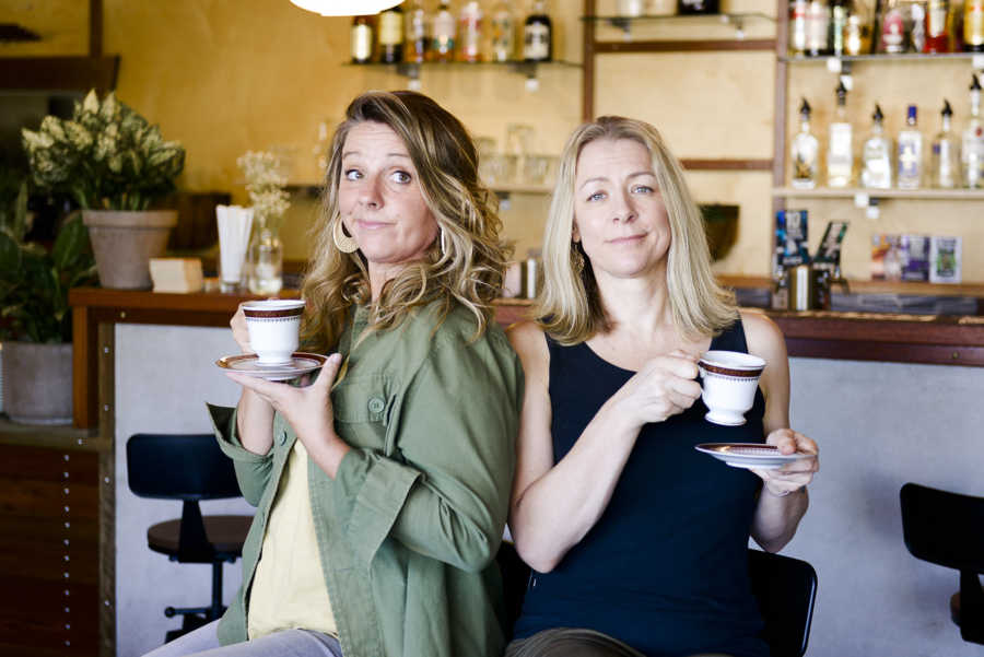 Two women at a bar holding teacups