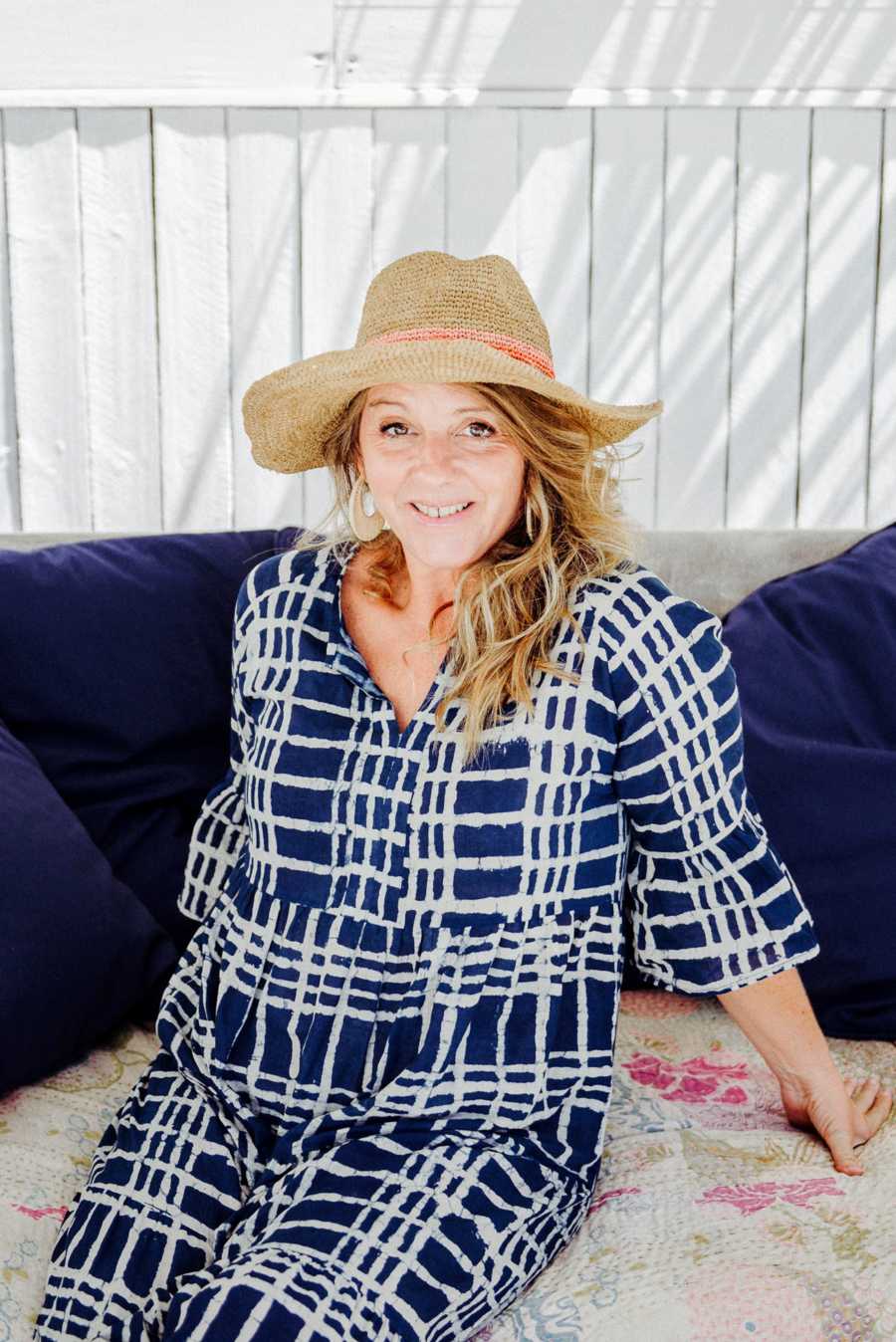 Woman wearing sunhat sitting on couch outside 