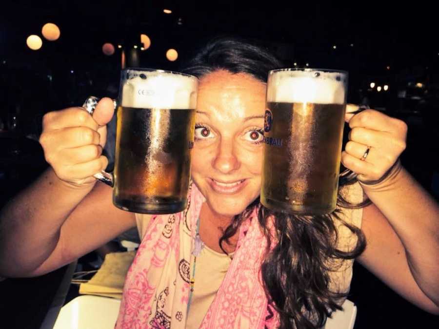 Woman at bar holding up two pints of beer