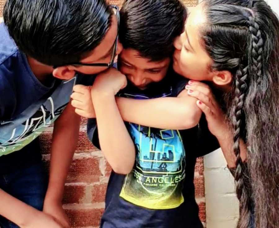 A boy with nonverbal autism is kissed by his siblings