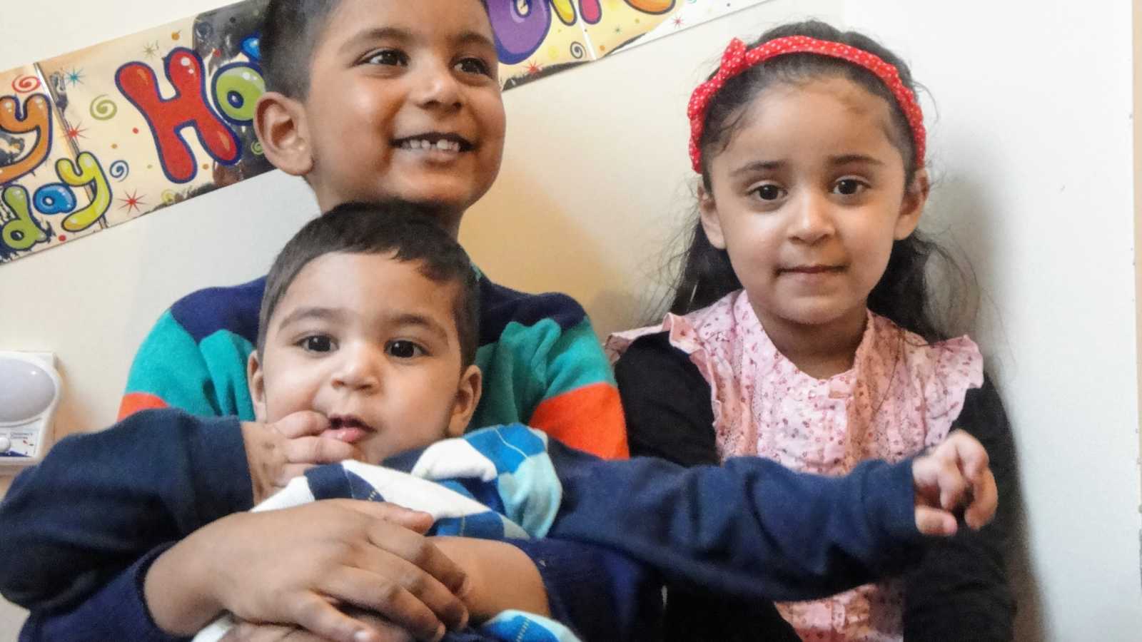 A boy with nonverbal autism sits with his brother and sister