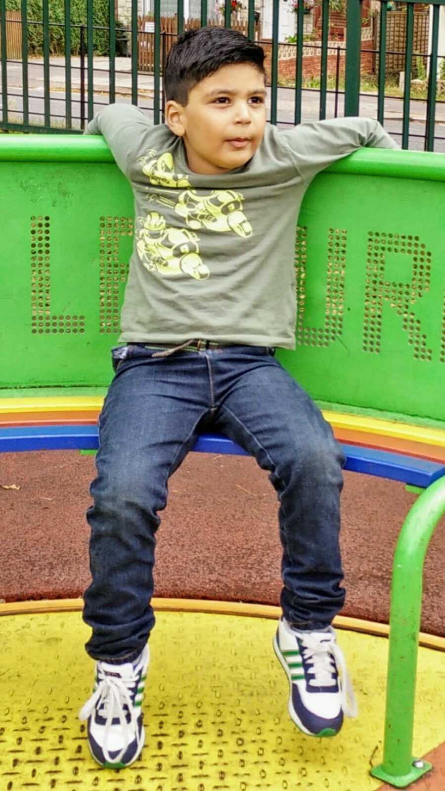 A boy with nonverbal autism sits on a playground